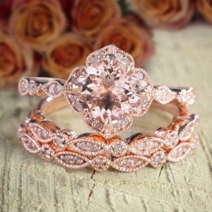 May include: A rose gold engagement ring set with a large, round morganite centre stone and smaller diamond accents. The ring is set in a delicate floral design.