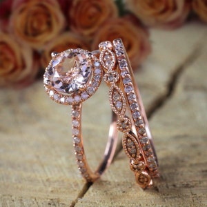 May include: A rose gold engagement ring set featuring a large round morganite centre stone surrounded by a halo of smaller diamonds. The set includes two matching bands with pavé diamonds and a delicate floral design.