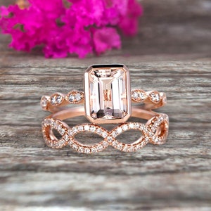 May include: A rose gold engagement ring set with a large, clear, emerald-cut center stone and smaller diamonds on the band. The wedding band is a delicate, intertwined design with diamonds.