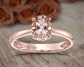 May include: A rose gold engagement ring with a large oval-shaped morganite gemstone. The ring is marked with "10K" on the band.