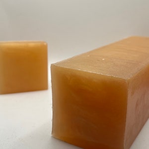 May include: Two bars of translucent amber-colored soap. The larger bar is rectangular and the smaller bar is square.