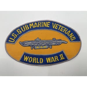 May include: A vintage patch with the text "U.S. SUBMARINE VETERANS" in blue lettering on a yellow background. The patch features a gray submarine illustration and the words "WORLD WAR II" in blue.
