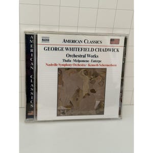 May include: A CD case featuring "American Classics" with "George Whitefield Chadwick: Orchestral Works." The cover displays text and a painting. The CD case has a clear plastic front and a spine that reads "American Classics."