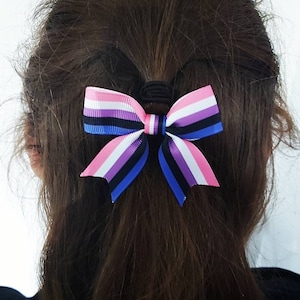 May include: A pink, purple, black and blue striped bow with a black hair tie.