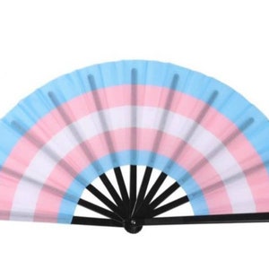 May include: A hand fan with a black handle and a blue, pink, and white fabric design. The fabric design is reminiscent of the transgender pride flag.