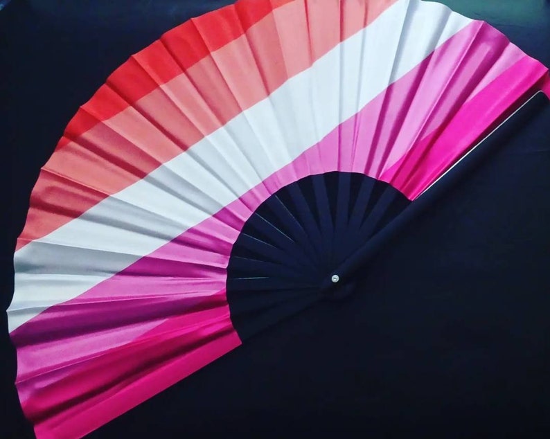 May include: A hand fan with a black handle and a pink, white, and red striped fabric design.