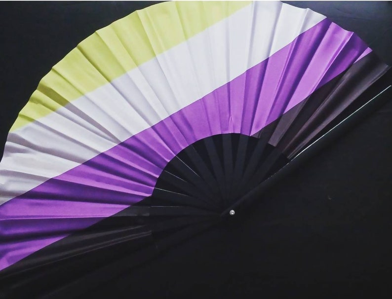 May include: A black folding fan with yellow, white, and purple stripes. The fan is closed and has a black handle.