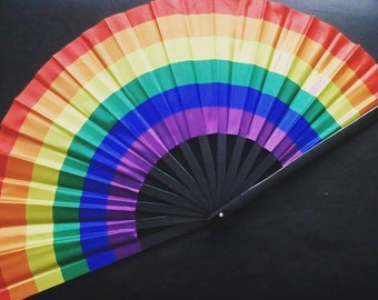 May include: A rainbow-colored folding fan with a black handle. The fan is made of fabric and has a rainbow pattern.