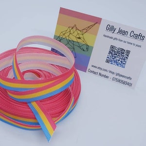 Peut inclure: Un rouleau de ruban rayé rose, bleu et jaune. Le ruban est enroulé sur lui-même et prêt à être utilisé pour des projets d'artisanat. Le ruban mesure 2,5 cm de large. Le ruban est fabriqué par Gilly Jean Crafts.