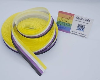 May include: A roll of yellow, white, purple, and black striped ribbon. The ribbon is a representation of the non-binary pride flag.