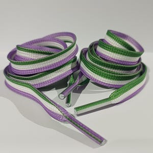 May include: Shoelaces in a coiled arrangement, featuring a striped pattern of purple, white, and green. The laces are made of a woven material and have plastic aglets on the ends. The color scheme is vibrant and eye-catching.