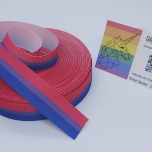 Op de afbeelding: Een rol blauwe, roze en witte ombre-lint. Het lint is 2,5 cm breed en perfect voor knutselprojecten. Het lint wordt getoond met een visitekaartje waarop "Gilly Jean Crafts" staat en een contactnummer en website.