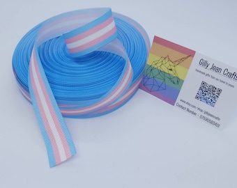 May include: A roll of light blue ribbon with a pink, white, and light blue striped design. A small card with a rainbow unicorn logo and the text "Gilly Jean Crafts" is next to the ribbon.