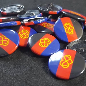 May include: A group of 12 round, black, red, and blue buttons with a gold infinity symbol and a heart inside. The buttons have a pin back.