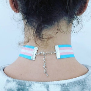 May include: A choker necklace with a light blue, pink and white ribbon, featuring a silver chain closure.