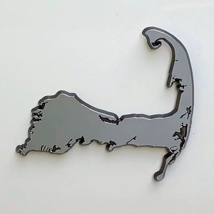 May include: A silver-colored metal cutout of the shape of Cape Cod, Massachusetts.