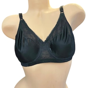 May include: A black bra with adjustable straps and a classic design. The bra features a lace trim along the neckline and a smooth, satin-like fabric on the cups. The bra is displayed on a mannequin.