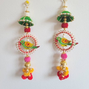 May include: Two green, red, and yellow tassel ornaments with a painted bird design and white pearl accents.