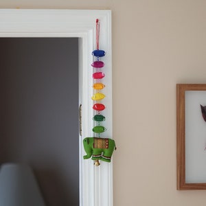 May include: A colorful door hanging with a rainbow of fabric ovals and a green felt elephant at the bottom.