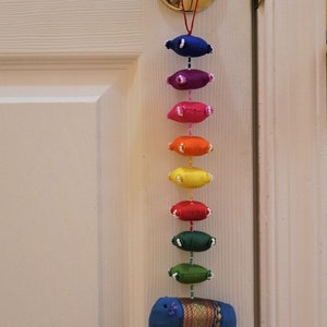 May include: A colorful door hanging with a rainbow of fabric ovals and a blue elephant at the bottom. The elephant has a gold trim and a bell. The text "Sky blue" is written on the door.