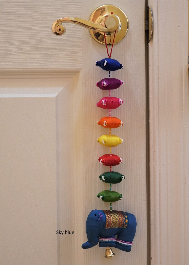 May include: A colorful door hanging with a rainbow of fabric ovals and a blue elephant at the bottom. The elephant has a gold trim and a bell. The text "Sky blue" is written on the door.