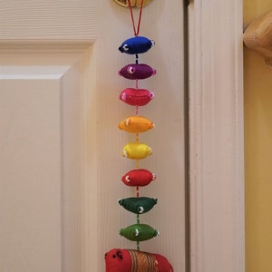 May include: A colorful door hanging with a red elephant at the bottom. The hanging features a series of fabric ovals in rainbow colors, each with white beads around the edges.