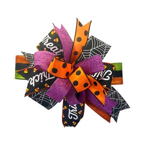 May include: A Halloween-themed bow with orange, black, and purple ribbons. The ribbons feature polka dots, candy corn, and the words "Trick or Treat".
