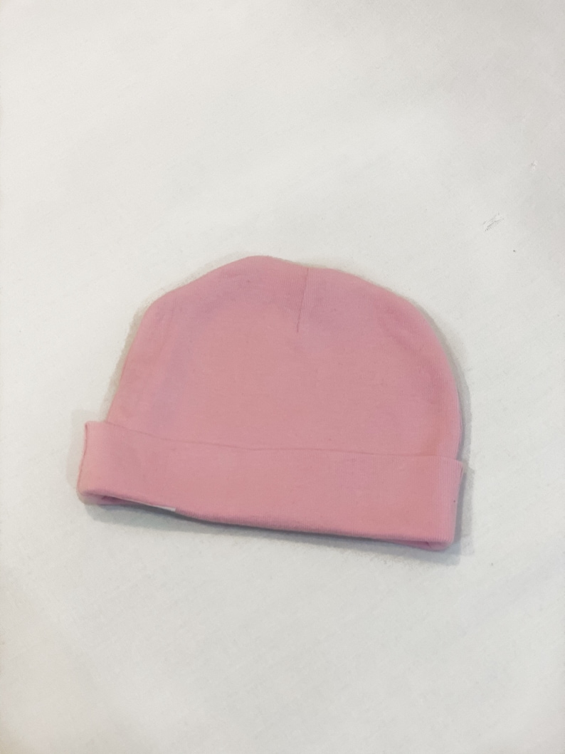 May include: A plain pink baby beanie hat.