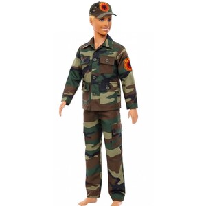 May include: A doll wearing a camouflage military uniform, including a jacket, pants, and a cap. The uniform features shades of green, brown, and black. The cap has a circular emblem. The doll is standing against a white background.
