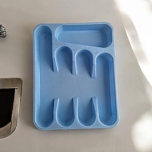 K&ouml;nnte beinhalten: Ein hellblaues Plastik-Bestecktablett mit sechs F&auml;chern f&uuml;r Besteck. Das Tablett ist rechteckig und daf&uuml;r ausgelegt, Gabeln, L&ouml;ffel und Messer aufzunehmen.