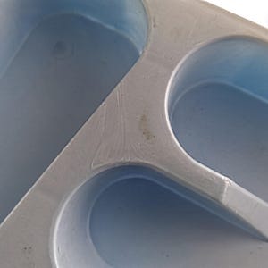 K&ouml;nnte beinhalten: Nahaufnahme einer grauen Plastikform mit drei ovalen Vertiefungen. Die Form ist zum Herstellen von Eisw&uuml;rfeln oder anderen kleinen Gegenst&auml;nden gedacht.