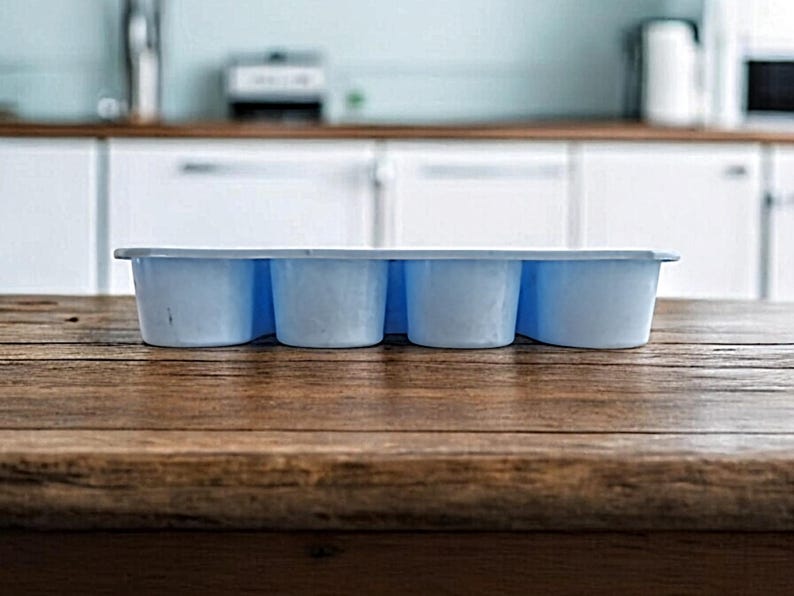 K&ouml;nnte beinhalten: Eine hellblaue Silikon-Eisw&uuml;rfelform mit sechs einzelnen F&auml;chern. Die Form steht auf einer Holzoberfl&auml;che.