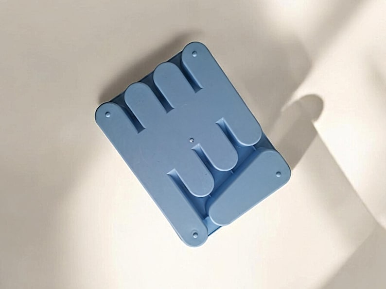 K&ouml;nnte beinhalten: Ein hellblauer Telefonst&auml;nder aus Kunststoff mit einem einzigartigen Design, der sich zum einfachen Verstauen zusammenklappen l&auml;sst.