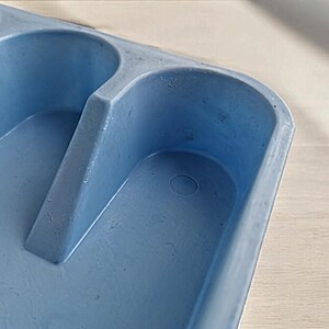 K&ouml;nnte beinhalten: Ein hellblaues Plastiktablett mit drei vertieften Abschnitten. Das Tablett hat eine kleine kreisf&ouml;rmige Vertiefung im unteren Abschnitt.