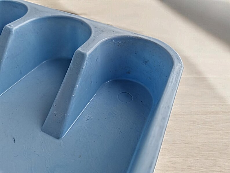 K&ouml;nnte beinhalten: Ein hellblaues Plastiktablett mit drei vertieften Abschnitten. Das Tablett hat eine kleine kreisf&ouml;rmige Vertiefung im unteren Abschnitt.