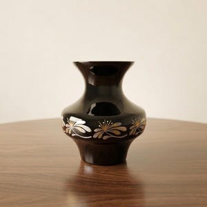 May include: A white ceramic mug with a black handle and the text "But First, Coffee" in a bold, black font. The mug is set against a blurred background, suggesting a cozy setting.