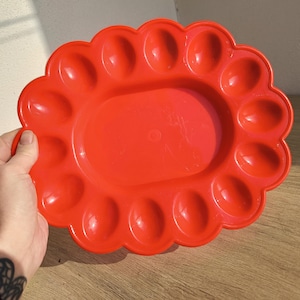 Puede incluir: Una bandeja para huevos de plástico rojo brillante con 12 compartimentos individuales para guardar huevos.
