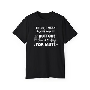 Peut inclure: Un t-shirt noir à manches courtes avec le texte blanc suivant : I DIDN'T MEAN to push all your BUTTONS I was looking FOR MUTE. Le motif comprend un petit graphique de télécommande et deux symboles en forme d'étoile sur le devant.