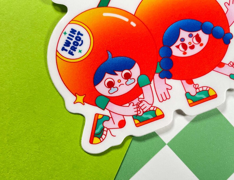 Puede incluir: Dos personajes de dibujos animados vestidos de fruta. Uno es una naranja con el texto "Twin Froot" en ella. El otro es una cereza roja. Ambos personajes llevan zapatos y tienen una expresi&oacute;n feliz.