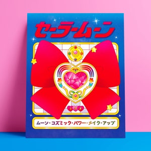 May include: A blue and white poster with the Japanese text "セーラームーン" and a red bow with a gold heart-shaped brooch in the center. The text at the bottom of the poster reads "ムーン・コズミック・パワー・メイク・アップ".