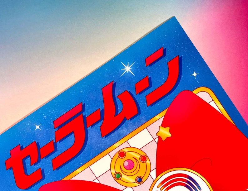 May include: A blue and red illustration of a Sailor Moon themed design with the Japanese text "セーラームーン" in red. The design features a star, a crescent moon, and a red bow.