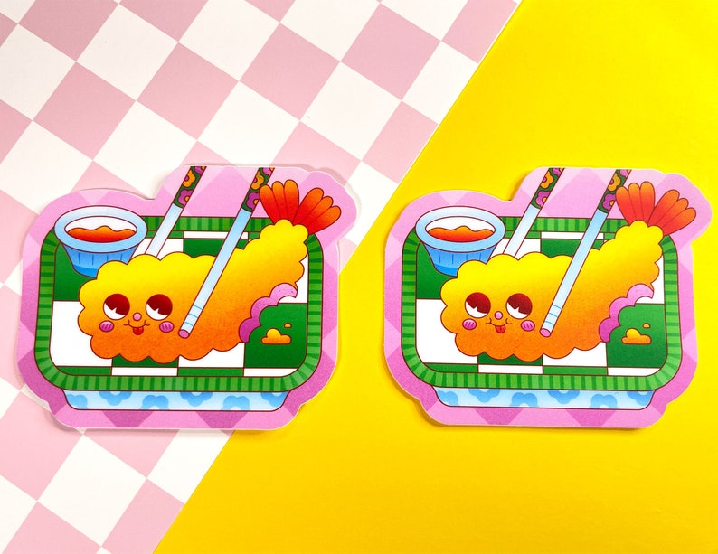 K&ouml;nnte beinhalten: Zwei rosa und gr&uuml;ne Cartoon-Aufkleber mit einer frittierten Garnele mit einem fr&ouml;hlichen Gesicht, Essst&auml;bchen und einer kleinen Sch&uuml;ssel mit orangefarbener Sauce. Die Aufkleber befinden sich auf einem rosa und wei&szlig;en karierten Hintergrund.