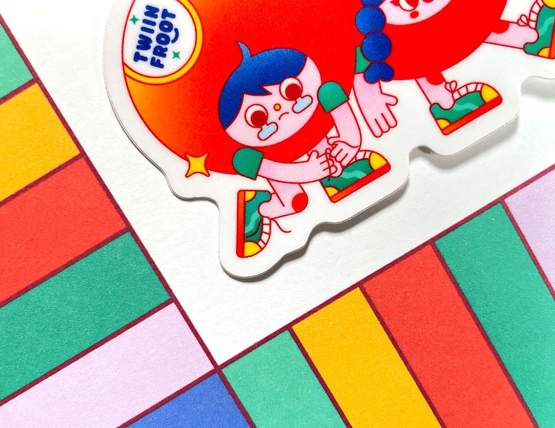 Puede incluir: Dos personajes de dibujos animados con ropa roja y verde y cabello azul. Los personajes se toman de la mano y sonr&iacute;en. Los personajes est&aacute;n sobre un fondo blanco con una pegatina que dice "Twin Froot".