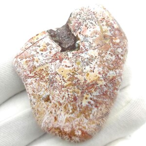 May include: A heart-shaped piece of agate with a white, brown, and red pattern. The agate has a natural, rough texture.