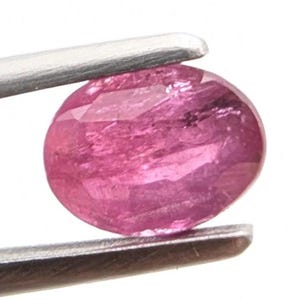 May include: A pink, oval-cut gemstone is held by silver tweezers. The gem is translucent with internal veining and a polished surface. The colour is a vibrant, medium pink, with variations in tone throughout the stone.