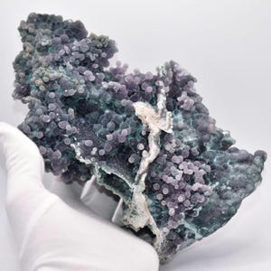 May include: A large, irregularly shaped piece of purple and green agate with a unique, bubbly texture. The agate has a natural, rough surface and is a beautiful example of this type of gemstone.