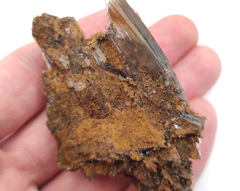 May include: A cluster of brown and clear crystals with a rough, textured surface. The crystals are arranged in a jagged, pointed shape.