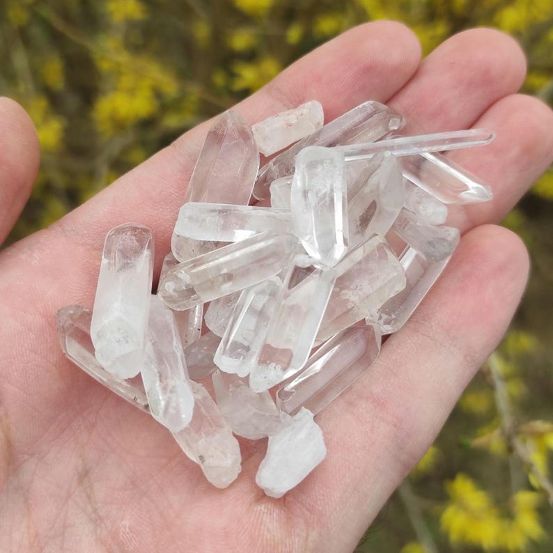 May include: A collection of clear quartz crystal points, also known as rock crystals, in various sizes and shapes. The crystals are arranged in a pile, showcasing their natural beauty and clarity.