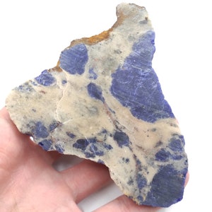 May include: A large, irregularly shaped piece of lapis lazuli with a white and blue marbled pattern. The stone has a rough, natural texture.