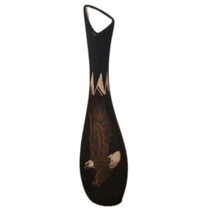 May include: A tall, slender black vase with a tapered neck and an angled rim. The body features a detailed graphic of a bald eagle in flight with brown and white plumage, and a white geometric triangular pattern encircling the upper section.